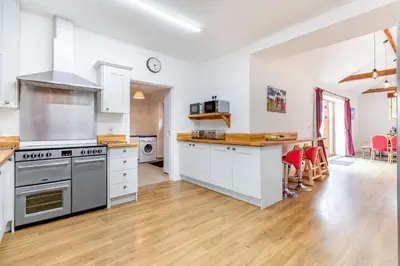 a large kitchen with white cabinets and a wooden floor at 6 Bed in Three Holes oc-t31855 in Upwell