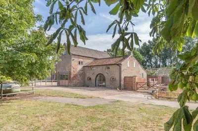 an old stone building with a gate and trees at 6 Bed in Three Holes oc-t31855 in Upwell
