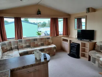 a living room with a couch and a fireplace at Comfortable and Spacious Mobile home - Sleeps 6, in Clacton-on-Sea