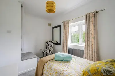a bedroom with a bed and a window and a chair at Rosabelle in Wivenhoe