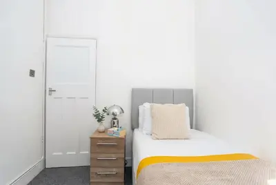 a bedroom with a bed and a dresser with a mirror at Modern 3 Bedroom Home with Parking in Southend in Southend-on-Sea