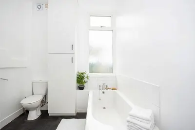 a white bathroom with a tub and a toilet at Modern 3 Bedroom Home with Parking in Southend in Southend-on-Sea