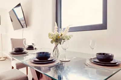 a dining room table with plates and glasses on it at The Opulent Property Project Penthouse Chelmsford 2 Bed 2 Bath Sleeps 6 Free Parking 2 Kings or 4 singles and Double Sofabed Ideal for long stays, corporates, families, Insurance in Chelmsford