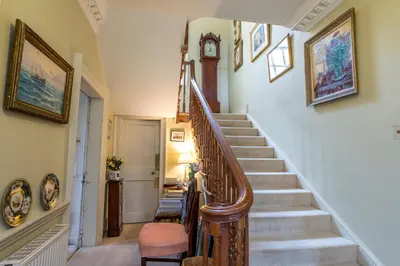 a staircase in a home with a clock on the wall at Holbecks House by Group Retreats in Hadleigh