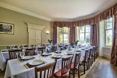 a conference room with tables and chairs and windows at Holbecks House by Group Retreats in Hadleigh