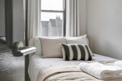 a white bed with a pillow and a window at Cambridge City Centre by Luxiety Stays Stylish Rooms, Prime Location & Wi-Fi in Cambridge