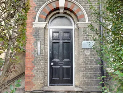 a black door on the side of a brick building at Cambridge City Centre by Luxiety Stays Stylish Rooms, Prime Location & Wi-Fi in Cambridge
