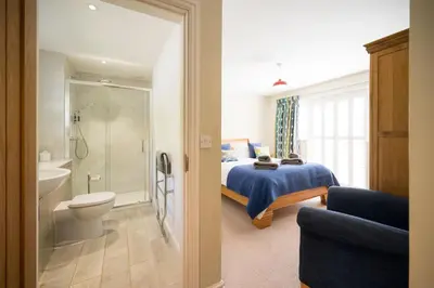 a bedroom with a bed and a bathroom with a toilet at Woodland Lodge, Aldeburgh in Aldeburgh