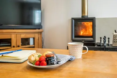 a plate of food and fruit on a table with a fireplace at Woodland Lodge, Aldeburgh in Aldeburgh