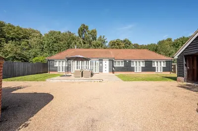 a house with a driveway in front of it at Woodland Lodge, Aldeburgh in Aldeburgh