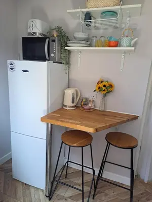 a small kitchen with a table and a refrigerator at Whole Annexe in our family home & private entrance in Ipswich