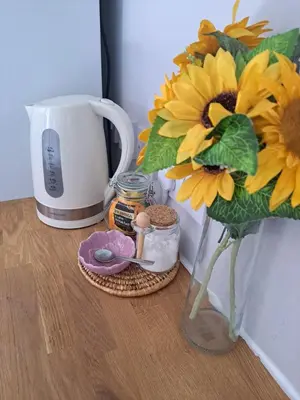 a table with a vase of sunflowers and a coffee maker at Whole Annexe in our family home & private entrance in Ipswich