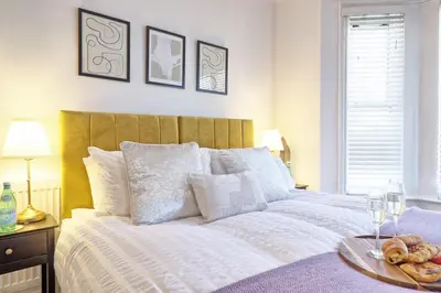 a bedroom with a bed with a tray of donuts on it at The Opulent Property Project Southend Beach House Sleeps 8 Free Parking x 2 Perfect for Contractors 4 King Beds or 8 Single Beds in Southend-on-Sea