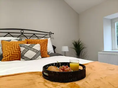 a tray of fruit on a bed with a glass of orange juice at Stylish 2-Bed Home Near A11 in Thetford