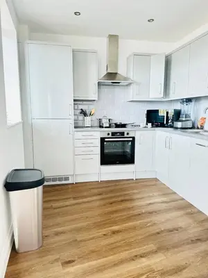 a white kitchen with wooden floors and white cabinets at Gorgeous two bedroom luxury Apartment sleeps 6 in Brentwood