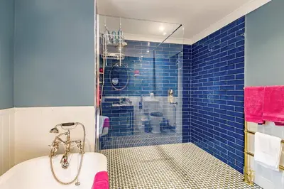 a bathroom with a tub and a shower with blue tiles at 1 Bed in Wymondham oc-e32664 in Wymondham