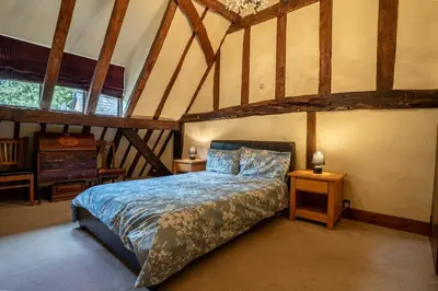 a bedroom with a bed in a room with wooden ceilings at Group Stays 600-Year-Old Barn, sleeps 11 in Great Parndon