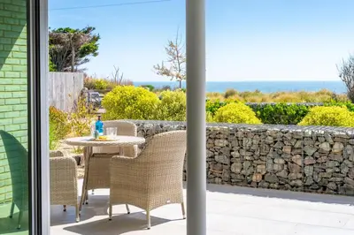a patio with a table and chairs and a stone wall at Heath House 6 in Thorpeness