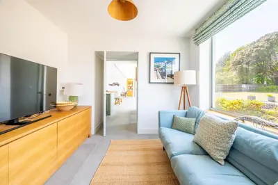 a living room with a blue couch and a large window at Heath House 6 in Thorpeness