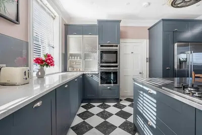 a kitchen with blue cabinets and a checkered floor at 6 Bedroom - Luxury - Cinema Room in Hertford