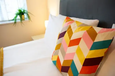 a colorful pillow sitting on top of a bed at 1 The Royal Serviced Apartments, Harwich SuperKing Bed, Parking, Fast WiFi in Parkeston