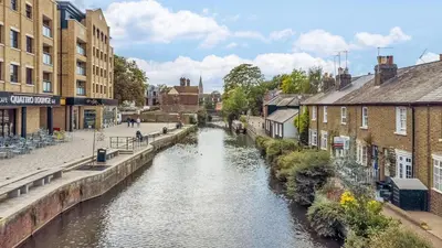 a river in the middle of a city with buildings at Riverside Cottage Retreat Hertford Town Sleeps 6 in Hertford