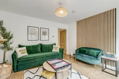 a living room with a green couch and a chair at Riverside Cottage Retreat Hertford Town Sleeps 6 in Hertford