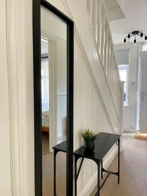 a mirror in a hallway with a table and stairs at Spacious 4-Bed Home Near Cambridge City Centre in Chesterton