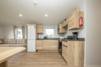a kitchen with wooden cabinets and a white refrigerator at New - 3 bedroom Caravan, 140 Pasture Lane in Great Clacton