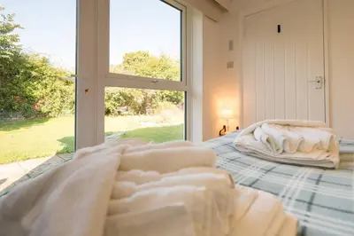 a bedroom with a bed with white sheets and a window at 5 Church Close (7 guests), Aldeburgh in Aldeburgh