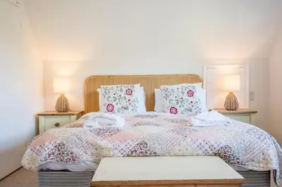 a bedroom with a large bed with two lamps at 5 Church Close (7 guests), Aldeburgh in Aldeburgh