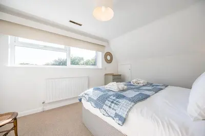 a white bedroom with a bed and a window at 5 Church Close (7 guests), Aldeburgh in Aldeburgh