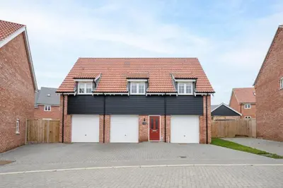 a brick house with a red roof and white garage at Stylish 2BR in Wickham Market in Wickham Market