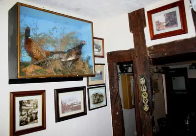 a painting of two birds on a wall with pictures at Farmhouse Inn in Thaxted