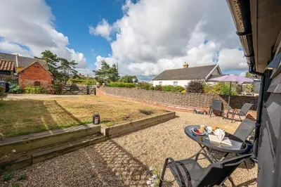 a patio with a table and chairs in a yard at 2 Beach Cottages, Thorpeness in Thorpeness