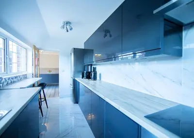 a kitchen with blue cabinets and a white counter top at Bright & Airy 4x Bed House with Parking in Ely