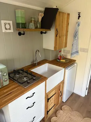a small kitchen with a sink and a stove at Shepherds hut in Holywell Cambridgeshire in Holywell