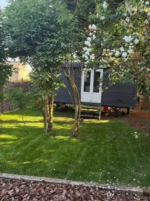 a cabin in a yard with a bench and trees at Shepherds hut in Holywell Cambridgeshire in Holywell