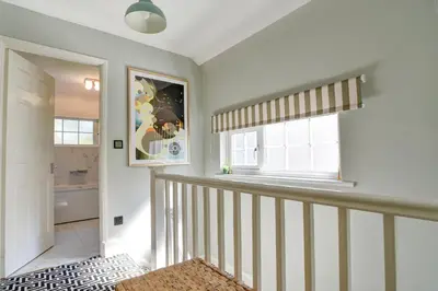 a hallway with a staircase with a window and a bathroom at Charming 4 bedroom home in Felsted in Felsted