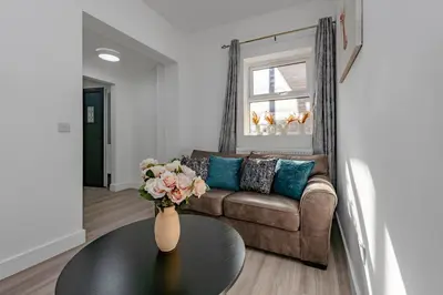 a living room with a couch and a vase with flowers on a table at Blue Horizon Seaside Apart in Clacton-on-Sea
