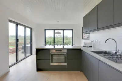 a kitchen with green and white counters and windows at Two bedroom house with far-reaching country views in Sheering