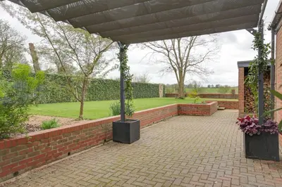 a brick patio with a pergola in a garden at Two bedroom house with far-reaching country views in Sheering