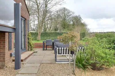 a patio with a table and benches in a garden at Two bedroom house with far-reaching country views in Sheering