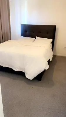 a bed with white sheets and a black headboard at Home in Colchester in Colchester