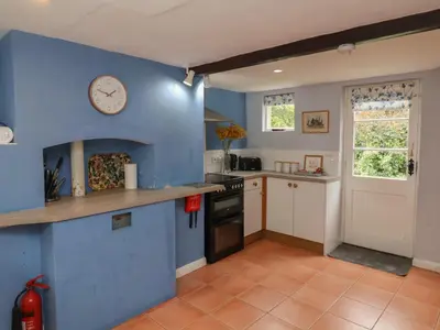 a kitchen with blue walls and a clock on the wall at Duchess Cottage in Woodbridge
