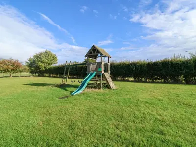 a playground with a slide in the middle of a field at Hayloft in Ipswich