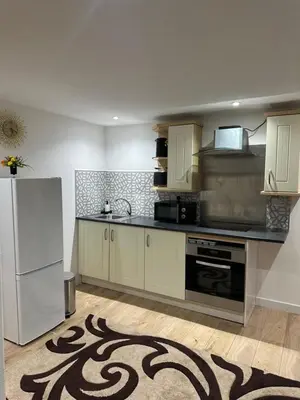 a kitchen with white cabinets and a white refrigerator at A Cosy and Spacious Studio Flat in Navestock