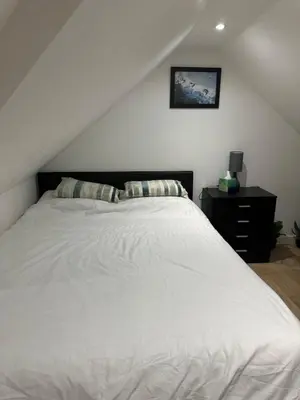 a bedroom with a white bed and a black dresser at A Cosy and Spacious Studio Flat in Navestock