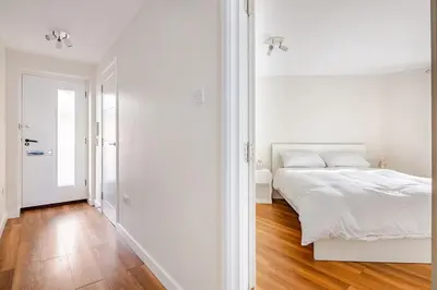 a white bedroom with a white bed and a wooden floor at Chic escape in Cambridge