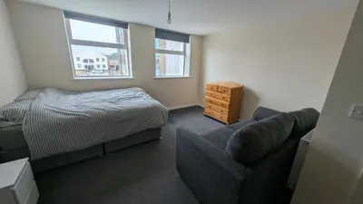 a bedroom with a bed and a couch and a chair at Harlech House Flats in Clacton-on-Sea